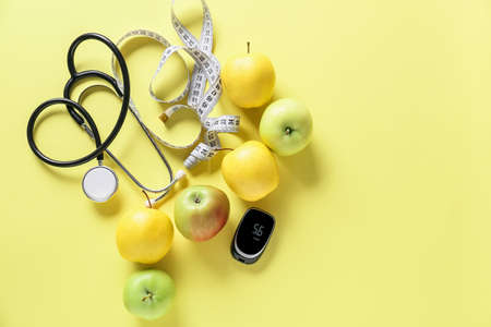 Fruits, measuring tape, stethoscope and glucometer on color background. Diabetes conceptの写真素材