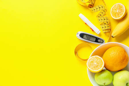 Fruits, measuring tape, lancet pen and glucometer on color background. Diabetes conceptの写真素材