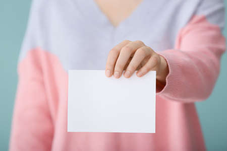 Woman with blank paper sheet on color backgroundの写真素材