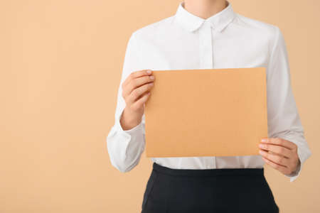 Woman with blank paper sheet on color backgroundの写真素材