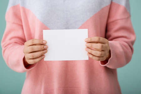Woman with blank paper sheet on color backgroundの写真素材