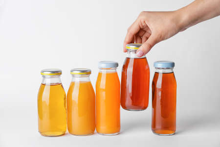 Female hand with bottles of juices on white background