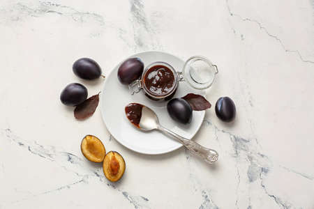 Glass jar with delicious homemade plum jam on table