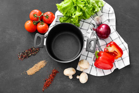 Composition with vegetables and cooking pot on dark background
