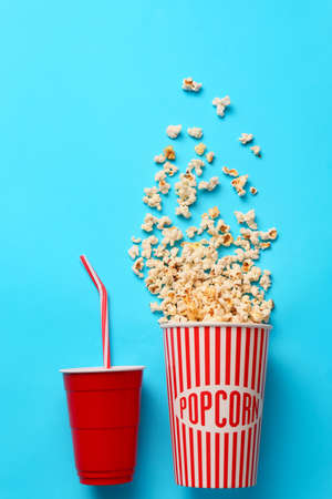 Tasty popcorn and cola on color background