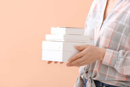Woman with blank cardboard boxes on color background