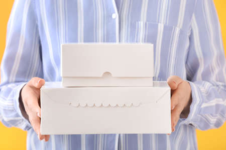 Woman with blank cardboard boxes on color background
