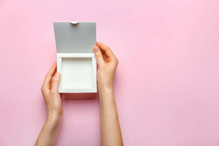 Hands with blank cardboard box on color background