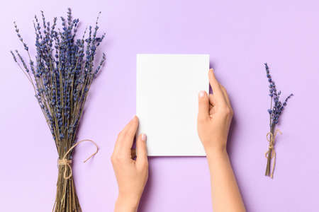 Female hands with blank paper sheet on color backgroundの写真素材