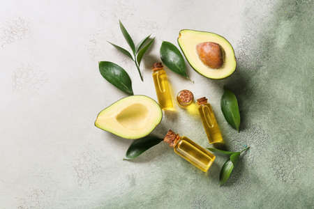Composition with bottles of essential oil and avocado on color backgroundの写真素材