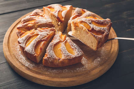 Board with tasty peach pie on dark backgroundの写真素材