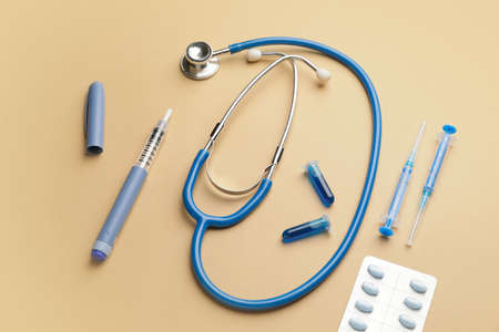 Stethoscope with pills and syringes on color background. Diabetes conceptの写真素材