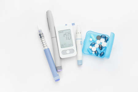 Glucometer, lancet pens, pills and syringe on white background. Diabetes conceptの写真素材