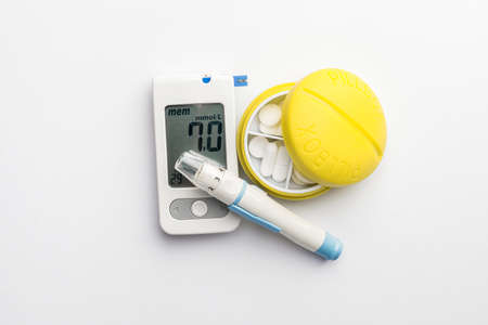 Glucometer, lancet pen and pills on white background. Diabetes concept