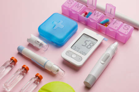 Glucometer with medications and lancet pens on color background. Diabetes conceptの写真素材