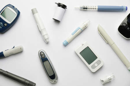 Glucometers with lancet pens and syringe on white backgroundの写真素材
