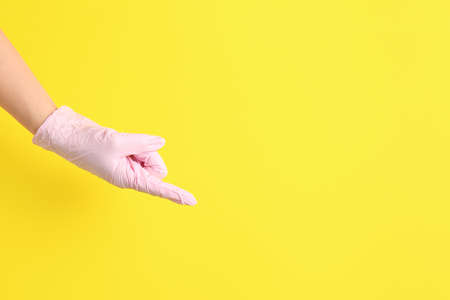 Hand in protective glove pointing at something on color backgroundの写真素材