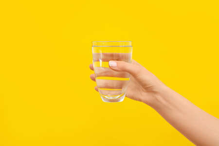 Hand with glass of water on color backgroundの写真素材