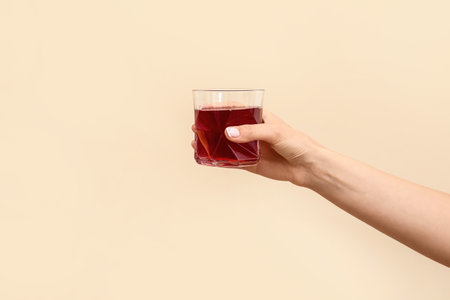 Hand with glass of beverage on color backgroundの写真素材