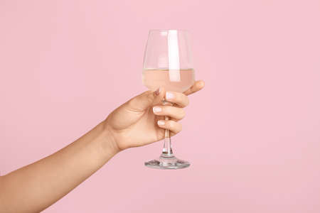 Hand with glass of wine on color backgroundの写真素材