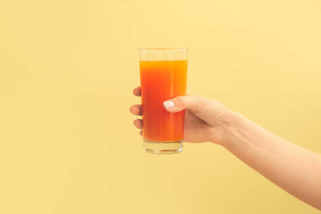 Hand with glass of fresh juice on color background