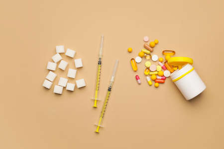 Sugar cubes, pills and syringes on color background. Diabetes conceptの写真素材