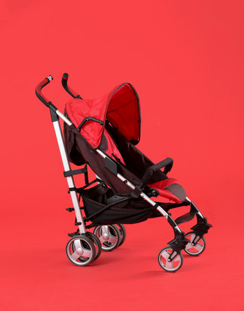 Modern baby stroller on color background