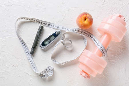 Glucometer with lancet pen, dumbbell and measuring tape on white background. Diabetes conceptの写真素材