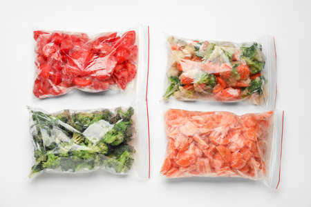 Plastic bags with frozen vegetables on white backgroundの写真素材