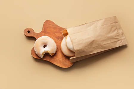 Tasty donuts in paper bag on color backgroundの写真素材