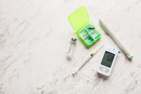 Glucometer with lancet pen, medications and syringe on white background. Diabetes conceptの写真素材