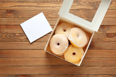 Box with tasty donuts on wooden backgroundの写真素材