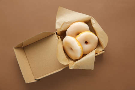Box with tasty donuts on color background