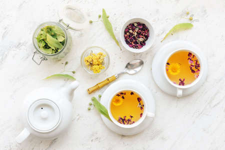 Herbs, teapot and cups with floral tea on light backgroundの写真素材