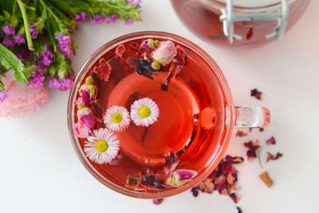 Flowers, teapot and cup with floral tea on light backgroundの写真素材