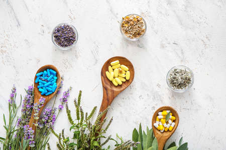 Wooden spoons with different plant based pills on light backgroundの写真素材