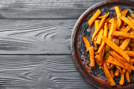 Board with tasty cooked sweet potato on wooden backgroundの写真素材