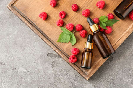 Bottles of raspberry essential oil on wooden trayの写真素材