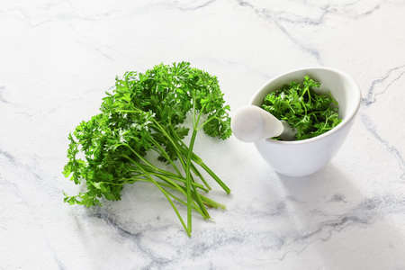Fresh parsley, mortar and pestle on light background