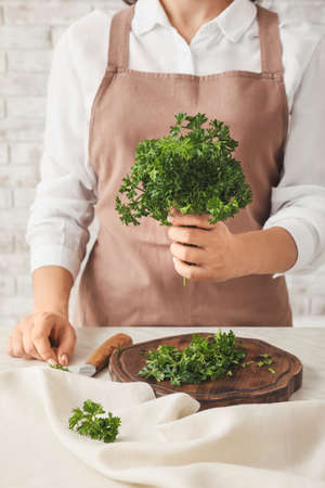 Woman with fresh parsley at tableの写真素材