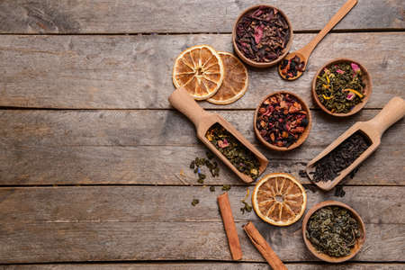 Bowls and spoons with dry tea leaves on wooden backgroundの写真素材