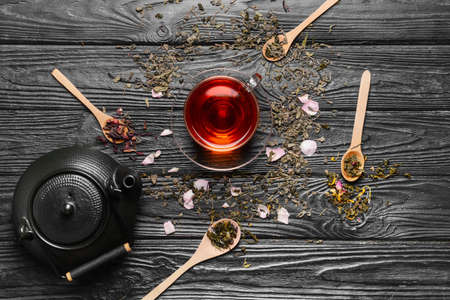 Composition with teapot, cup and dry tea leaves on wooden background