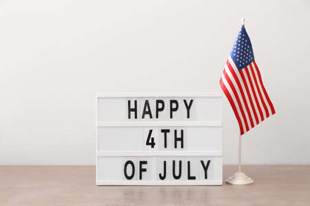 Board with text HAPPY 4TH of JULY and American flag on light backgroundの写真素材