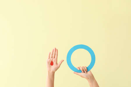 Female hands with blood drop and blue ring on color background. Diabetes concept