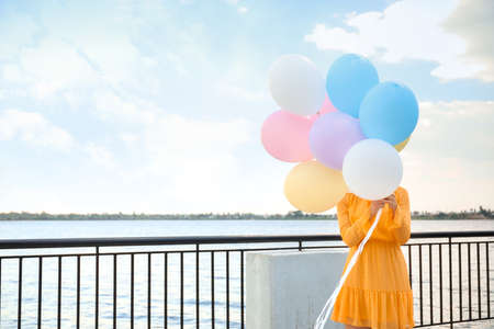 Young woman with balloons outdoors near riverの写真素材