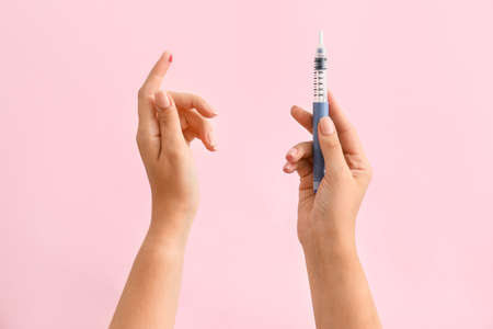 Female hands with blood drop and syringe on color background. Diabetes concept