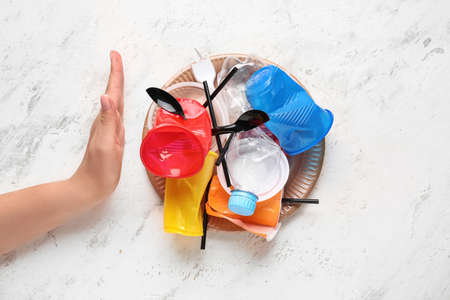 Female hand with plastic garbage showing stop gesture on white background. Ecology conceptの写真素材