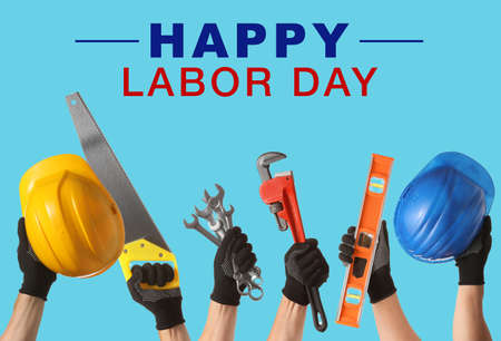Hands of workers with different tools on color background with text HAPPY LABOR DAYの写真素材