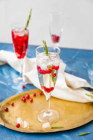 Glasses of champagne cocktail with cranberry and rosemary on color tableの写真素材