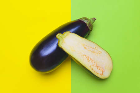 Fresh and sliced eggplants on color background